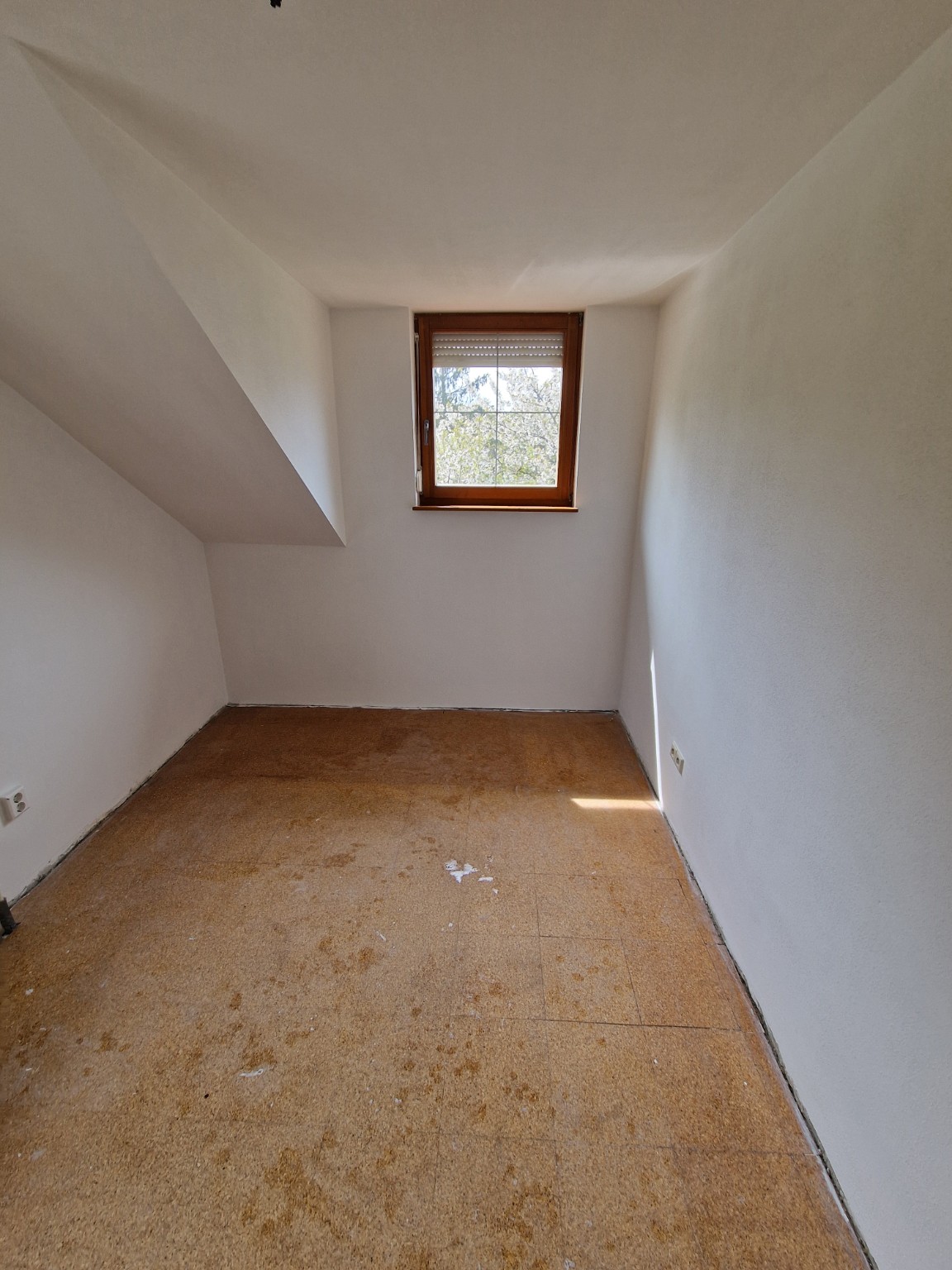 Dachzimmer mit fertigen weißen Wänden und vorbereitetem Boden